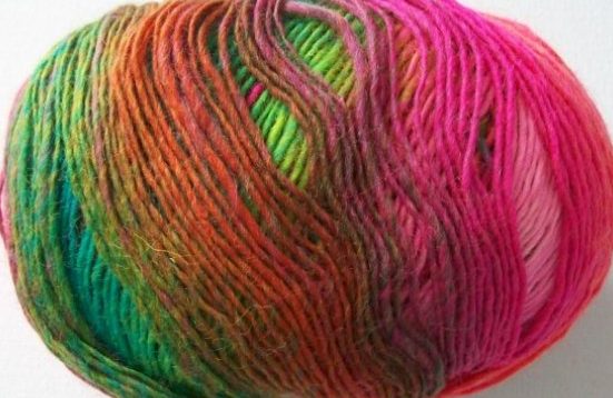 Wolle und Garne für Individualisten Buntes Wollknäul mit verlaufenden Farben in Pink, Grün und Orange.