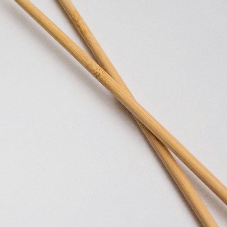 Die passenden Produkte für Ihre Ideen! Zwei Sticknadeln liegen sich kreuzend auf einer weißen Oberfläche.
